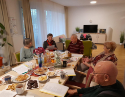 Senioren sitzen an einem gedeckten Weihnachtstisch, Weihnachtsfeier, Senioren-WGs