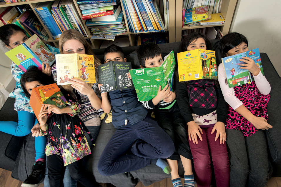 LernLEO - Kinder verstecken Gesichter hinter Büchern und liegen auf Sofa