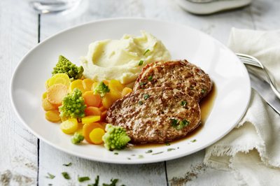 Essen auf Rädern Faschierte Laibchen mit Püree und Gemüse auf Teller angerichtet