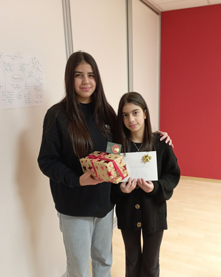 Zwei Mädchen stehen mit ihren Weihnachtsgeschenken beisammen und posieren für die Kamera