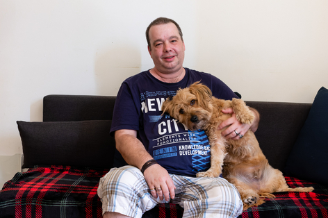 Einrichtungsbewohner sitzt mit seinem Hund auf Sofa