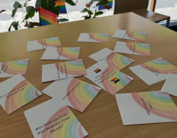 viele Zettel mit Fragen liegen auf dem Tisch, Regenbogen auf Papier