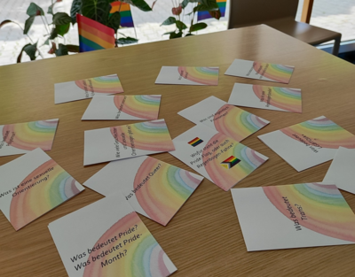 viele Zettel mit Fragen liegen auf dem Tisch, Regenbogen auf Papier