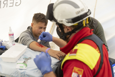 Sanitäter versorgt Wunde am Arm einer Person