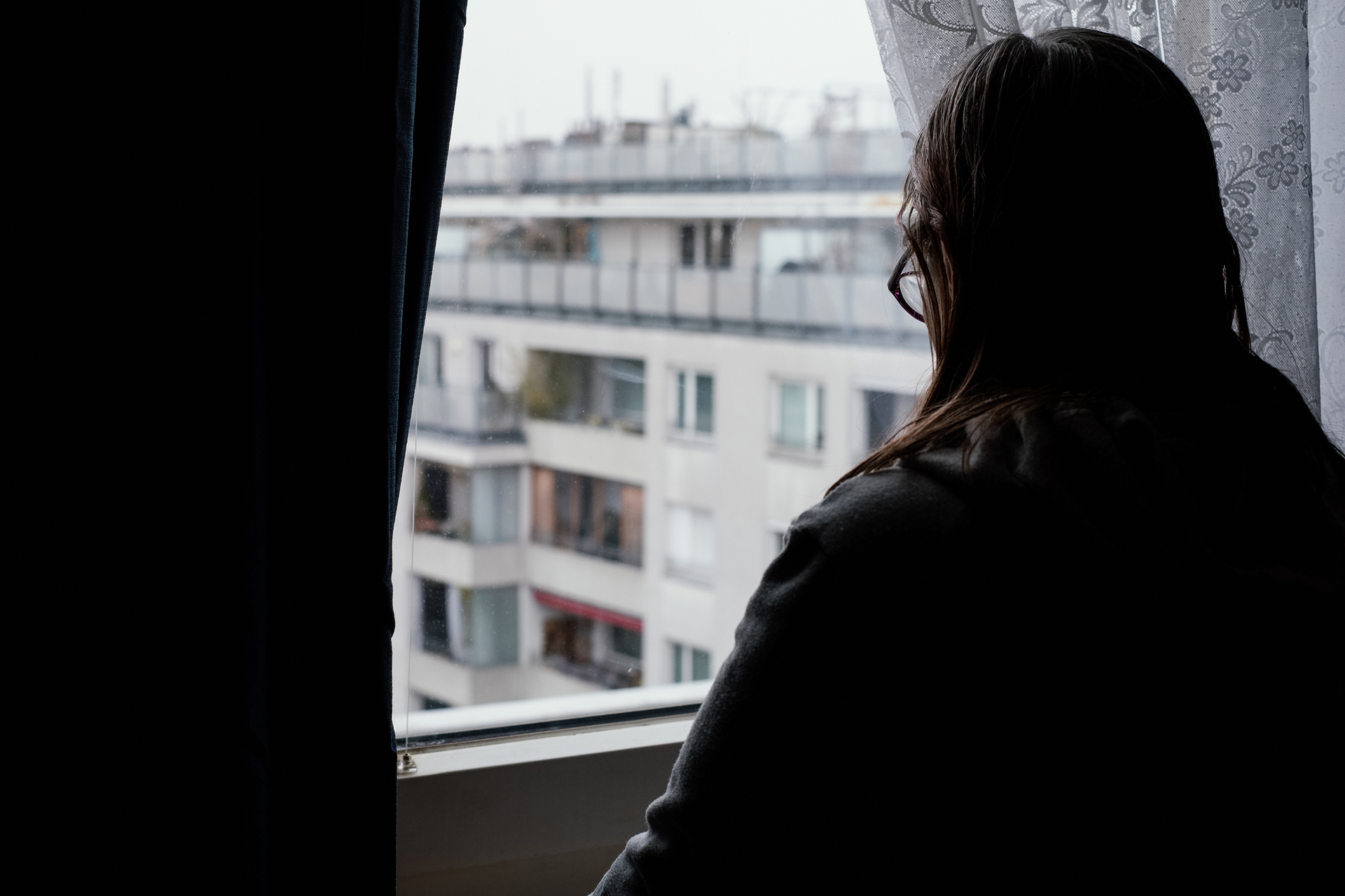 Von hinten fotografierte Frau sieht durch Fenster