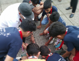 Gruppe von Kindern hockt gemeinsam am Boden, lösen eine Aufgabe