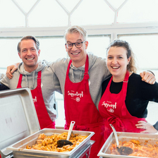 BAWAG-Team beim Suppentopf, 3 Personen hinter Chaving-Platten mit frisch gekochtem Essen.