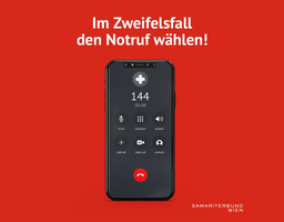 Handy mit der Notrufnummer 144 am Display vor rotem Hintergrund