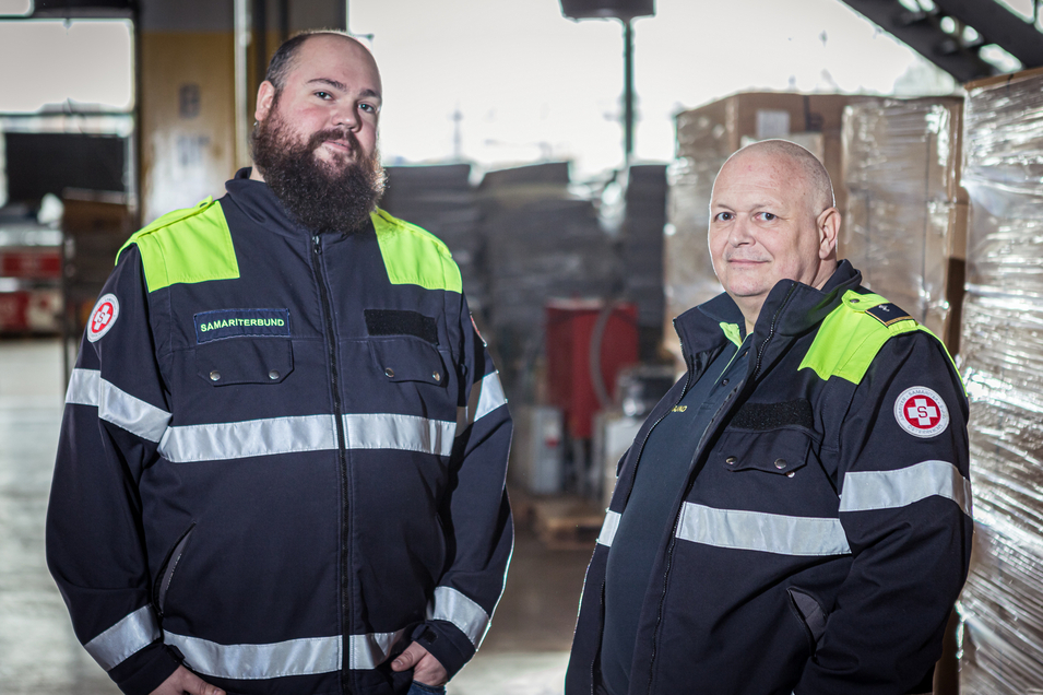 Zwei Mitarbeiter des Katastrophen Hilfsdienstes Samariterbund Wien schauen in die Kammera