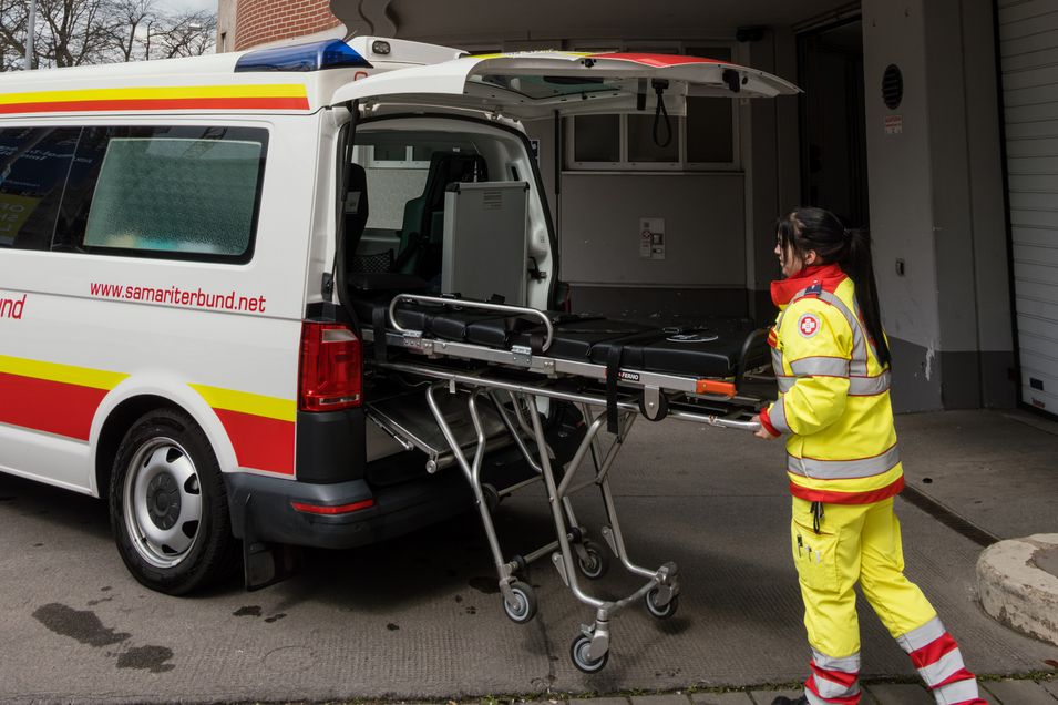 Sanitäterin belädt Krankenwagen mit Transportliege