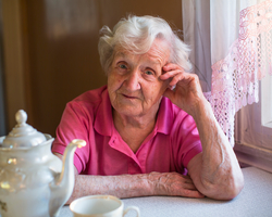 Ältere Dame sitzt in ihrer Wohnung.