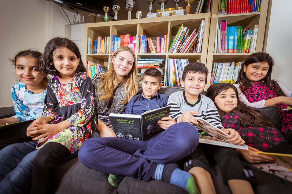Gruppenkinder sitzen zusammen und lesen Bücher in einer gemütlichen Umgebung.