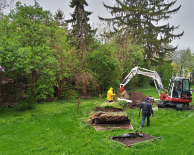 In einem Garten wird Erde mithilfe eines Bagger ausgegraben. 