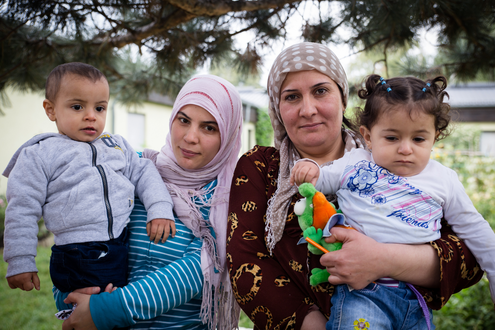 Zwei mit Kopftuch bedeckte Frauen mit Kindern am Arm