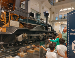 Kinder betrachten im Museum eine Eisenbahn