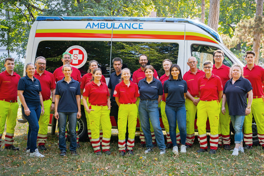 Gruppenfoto vom Schulungsteam vor einem Rettungsfahrzeug