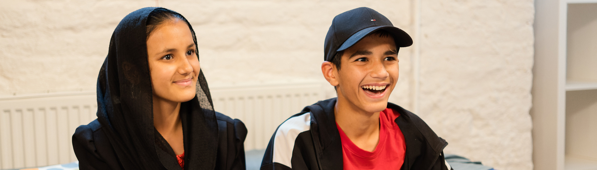 Zwei fröhliche Kinder sitzen auf einer Couch