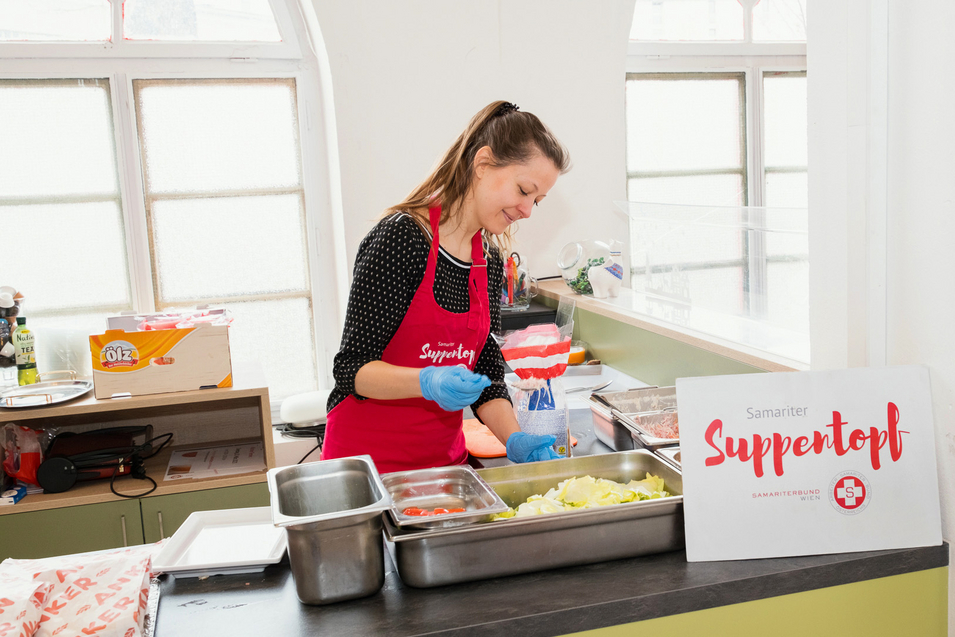 Eine Frau in roter Schürze vom Samariterbund trifft die letzten Vorbereitungen für das Essen.