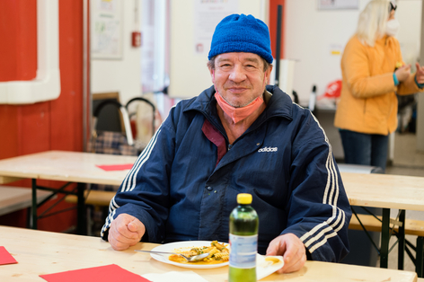 Älterer Mann mit Haube genießt seine warme Mahlzeit vom Samariter Suppentopf