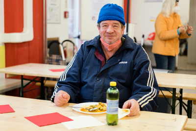 Mann mit Haube genießt Essen von Samariter Suppentopf