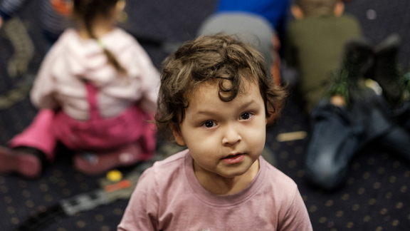 Kleinkind in Flüchtlingseinrichtung schmunzelt und sieht in die Kamera