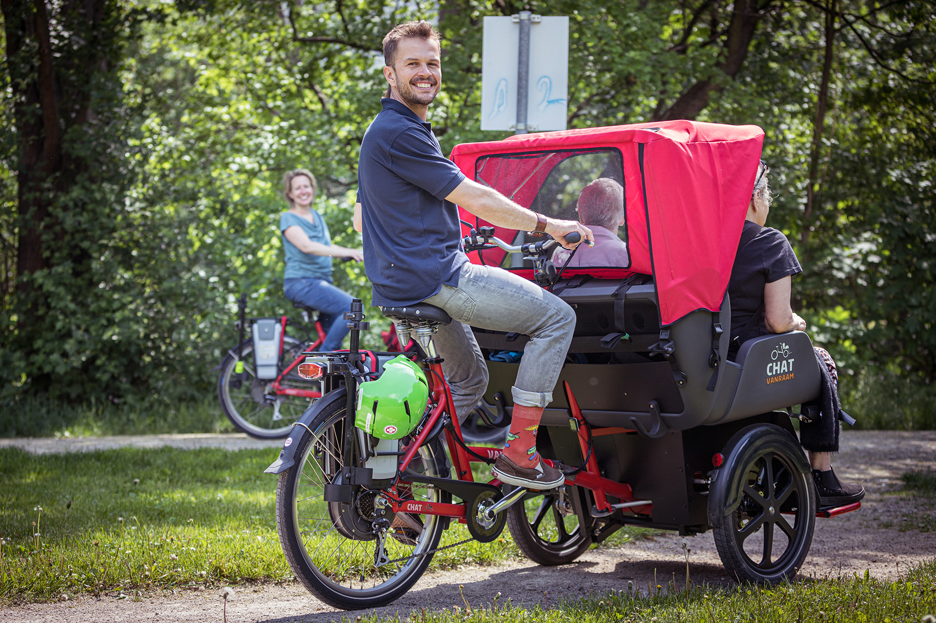 Ehrenamtlicher Rikscha-Fahrer transportiert zwei Personen durch Park
