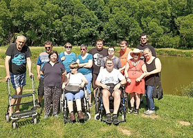 Gruppe von Menschen mit Behinderungen bei einem sonnigen Ausflug am Wasser.