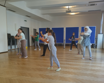 in einem Raum auf einer leeren Fläche probieren ein paar Kinder eine Koreografie aus und haben Spaß, LernLEO, Theaterworkshop,