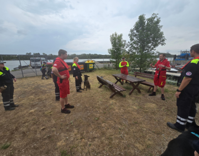 Personen von der Wasserrettung und der Rettungshundestaffel haben eine Besprechung.