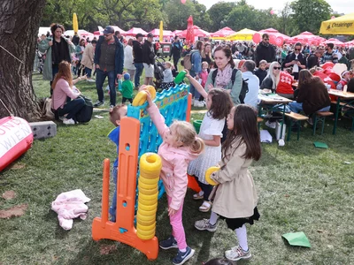 Vier Kinder spielen mit einem bunten Spielgerät im Freien. Im Hintergrund Veranstaltung Tag des Samariterbundes auf der Kaiserwiese im Prater.