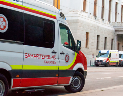 Ein Rettungstransportwagen des Samariterbund Wien ist zu sehen, im Hintergrund sind zwei weitere Rettungstransportwägen geparkt.