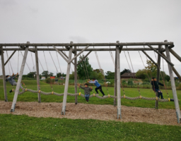 mehrere Kinder stehen auf großem Seil, schaukeln hin und her