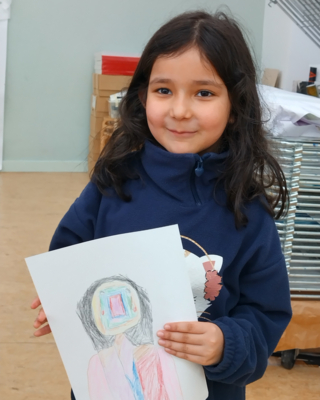 Auf dem Bild ist ein junges Mädchen zu sehen, das ein selbst gezeichnetes Bild in der Hand hält.