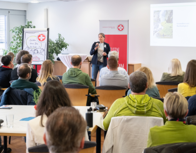 Gruppe von Menschen sitzen bei Vortrag, eine Vortragende