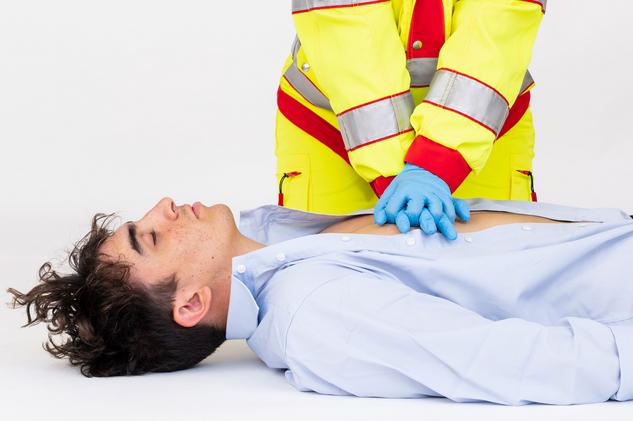Sanitäterin zeigt Herzdruckmassage an einem Patienten