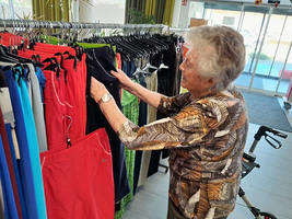 Eine ältere Frau wählt Hosen aus einem ausgehängten Sortiment aus.
