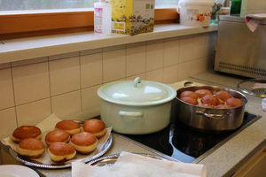 Selbstgemachte Donuts auf einem Küchentisch, einige in einem Topf, andere auf einem Teller.